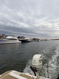 A scenic view of multiple yachts docked along the marina, showcasing the beauty of boating life against a cloudy sky.
