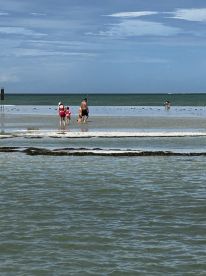 A family enjoys a day at the beach, wading through shallow waters and creating lasting memories during their sandbar adventure.