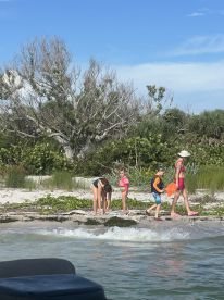 A family of children explores the shoreline, collecting treasures at a beautiful beach — a perfect sandbar stop for fun and adventure.