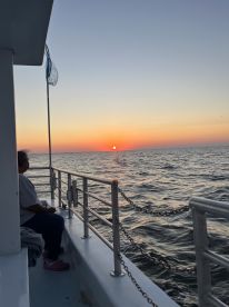 A serene sunset view from a boat with a guest enjoying the peaceful waters — a perfect moment for relaxation and reflection.