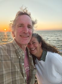 A couple enjoys a romantic sunset selfie on a boat, capturing a perfect moment of celebration on the water.