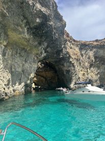 A stunning view of a cave with crystal-clear turquoise waters, featuring boats and people enjoying the scenic beauty — a perfect spot for exploration and adventure.