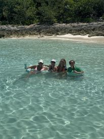 A cheerful group enjoys a refreshing swim in crystal-clear waters, perfect for beach celebrations and fun in the sun.