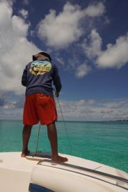 A crew member prepares for fishing on a boat, surrounded by stunning turquoise waters and a picturesque sky — perfect for adventure seekers and ocean enthusiasts.
