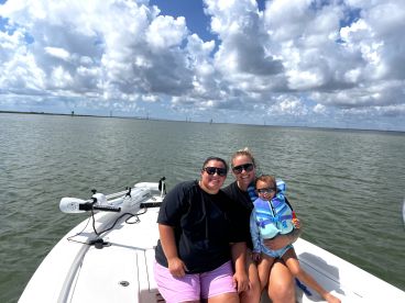 A joyful family enjoys a day on the water, capturing a memorable moment aboard their boat under a beautiful sky.