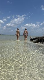 Two women enjoy a sunny day at the beach, wading through clear waters — a perfect scene for summer fun and relaxation.