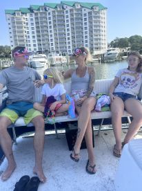 A family enjoys a relaxing day on the boat, showcasing fun moments and togetherness against a scenic waterfront backdrop.