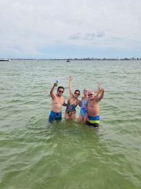 A lively group of friends celebrates in the water, enjoying a fun day at the beach — perfect for summer outings and memorable gatherings.