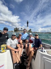 A group of friends enjoys a fun day on the water near a lighthouse, capturing the essence of camaraderie and adventure while boating.