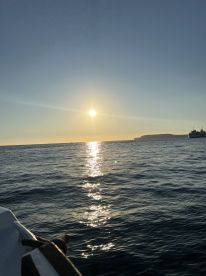 A serene sunset view over the water, with reflections shimmering on the surface, showcasing the tranquility of a boating experience.