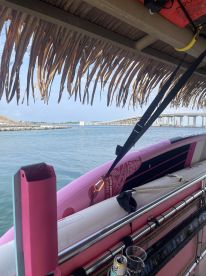 A vibrant pink paddleboard and cooler are displayed on a boat, showcasing the perfect setup for a fun day on the water.