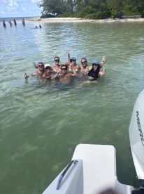A lively group enjoys a fun day in the water, celebrating with drinks and laughter at a beautiful beach location.