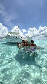 A lively group enjoys a refreshing swim in crystal-clear waters beside the 'SeaBlu' boat, capturing the essence of fun and adventure on the water.