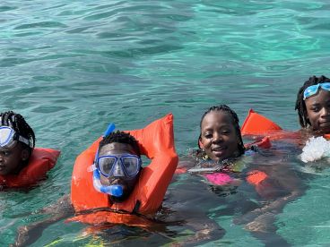 A group of young snorkelers enjoys swimming in crystal-clear waters, showcasing a fun and adventurous day on the water.