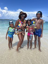 A joyful family interacts with a pig in shallow waters, creating a memorable wildlife experience in a tropical setting.