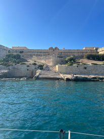A picturesque view of a historic landmark along the coastline, with people enjoying the sun and water — perfect for sightseeing and coastal adventures.