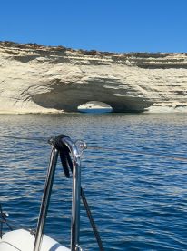 A stunning view of a natural rock arch from a boat, showcasing the beautiful coastline and clear waters — perfect for exploring scenic landmarks.