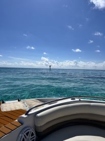 A stunning view from the deck of a boat, showcasing clear turquoise waters and a distant marker buoy under a bright blue sky — perfect for a day out on the water.