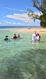 A lively group enjoys a sunny day swimming in clear waters at a beautiful beach, perfect for memorable outings and relaxation.