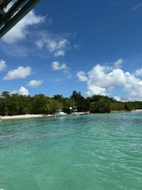 A picturesque view of a beach with boats anchored nearby and people enjoying the clear turquoise waters, perfect for a day of relaxation and fun in the sun.