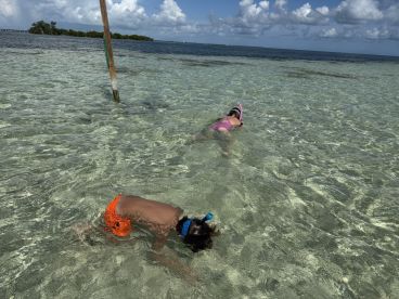 Two children enjoy snorkeling in crystal-clear waters, exploring the underwater world — a perfect family adventure in a tropical paradise.
