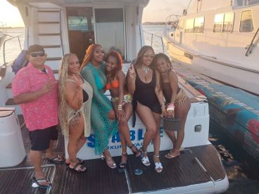A vibrant group of friends poses for a fun photo on the deck of a boat, capturing the essence of a lively boat party experience.