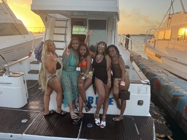 A vibrant group of friends poses for a fun photo on a boat at sunset, capturing the essence of a memorable celebration on the water.