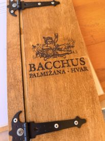 A beautifully crafted wooden menu from Bacchus in Palmizana, Hvar, showcasing the restaurant's offerings — perfect for dining experiences on the water.