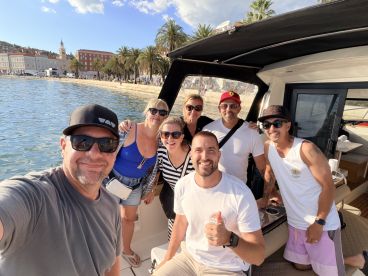 A cheerful group of friends poses for a selfie aboard a boat, capturing a memorable moment during their seaside adventure.