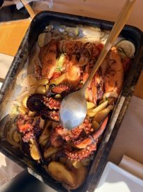 A delicious seafood platter featuring grilled octopus and assorted vegetables, perfect for onboard dining experiences.