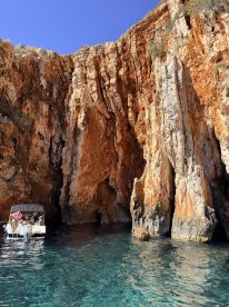 A group of people enjoys a scenic boat ride near stunning rocky cliffs, perfect for exploring hidden caves and enjoying the beauty of nature.