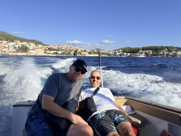 Two friends relax on a boat while enjoying the scenic coastline, capturing the essence of a fun day on the water.