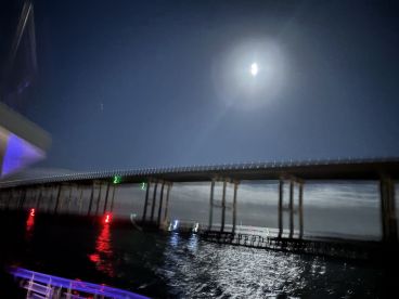 A nighttime image featuring a bridge and moonlight over the water, but the clarity is compromised, making it difficult to discern details.