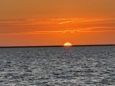A stunning sunset over calm waters, creating a picturesque scene perfect for romantic evenings or peaceful boat rides.