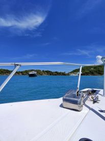 A scenic view from the deck of a boat, showcasing the tranquil blue waters and lush greenery in the background — perfect for a relaxing day on the water.