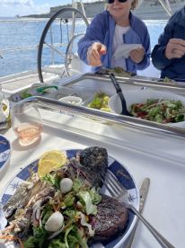 A beautifully plated meal featuring grilled fish and fresh salad, enjoyed on a boat — perfect for a gourmet dining experience at sea.