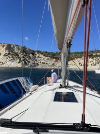A serene moment aboard a sailboat, with a guest enjoying the view of the stunning coastline — perfect for sailing enthusiasts and relaxation seekers.