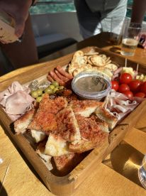 A beautifully arranged charcuterie board featuring a variety of meats, cheeses, and snacks, perfect for enjoying drinks on a boat.