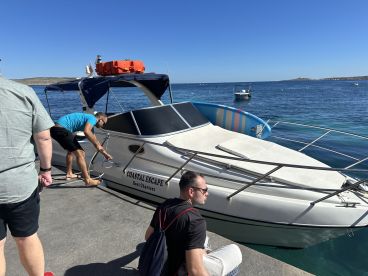 A group prepares to board the 'Coastal Escape' boat charter at the dock, showcasing a lively atmosphere before setting out on the water.