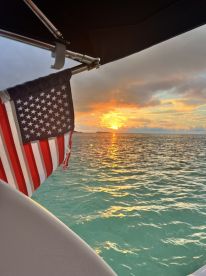 A stunning sunset view from a boat, featuring an American flag fluttering in the breeze — a perfect moment for a serene evening on the water.