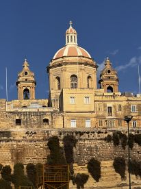 A view of a historic building with domes and intricate architecture, set against a clear blue sky. The image captures the essence of the location's rich cultural heritage.