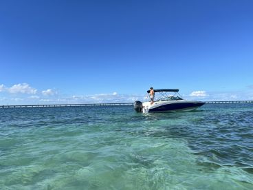 A person stands on a boat in clear turquoise waters, enjoying a sunny day on the water — perfect for adventure and relaxation.