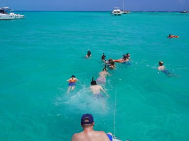 A lively group enjoys snorkeling in the crystal-clear turquoise waters, creating unforgettable memories on their aquatic adventure.
