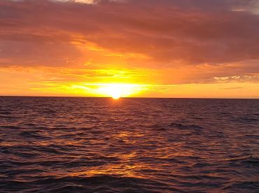 A stunning sunset over the ocean, casting vibrant colors across the water — perfect for serene evening boat rides.