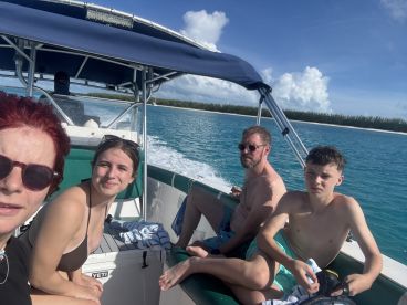 A group of friends enjoys a sunny day on the water, capturing a moment aboard their boat with beautiful scenery in the background.