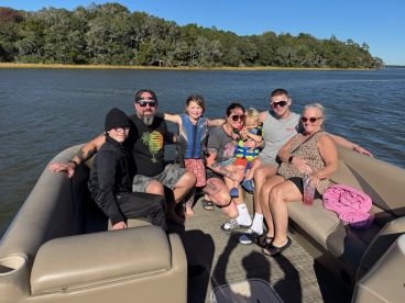 A joyful family gathers on a pontoon boat, enjoying a sunny day on the water — perfect for creating lasting memories together.