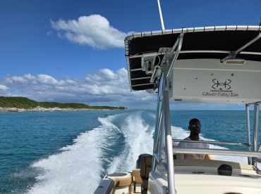 A captain navigates a fishing boat through crystal-clear waters, showcasing the beauty of the coastline — perfect for fishing adventures and scenic tours.