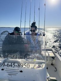 A couple enjoys a fishing trip on a charter boat, excitedly discussing their catch under the bright sun — a perfect day on the water.