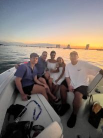 A group of friends enjoys a sunset boat ride, capturing a memorable moment together on the water.