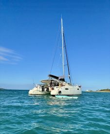 A stunning view of a catamaran anchored in clear turquoise waters, showcasing its sleek design against a bright blue sky — perfect for sailing adventures.